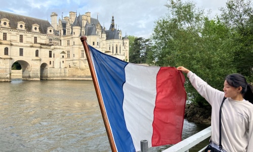 Student holding the French flag in front of Chenonceau castle